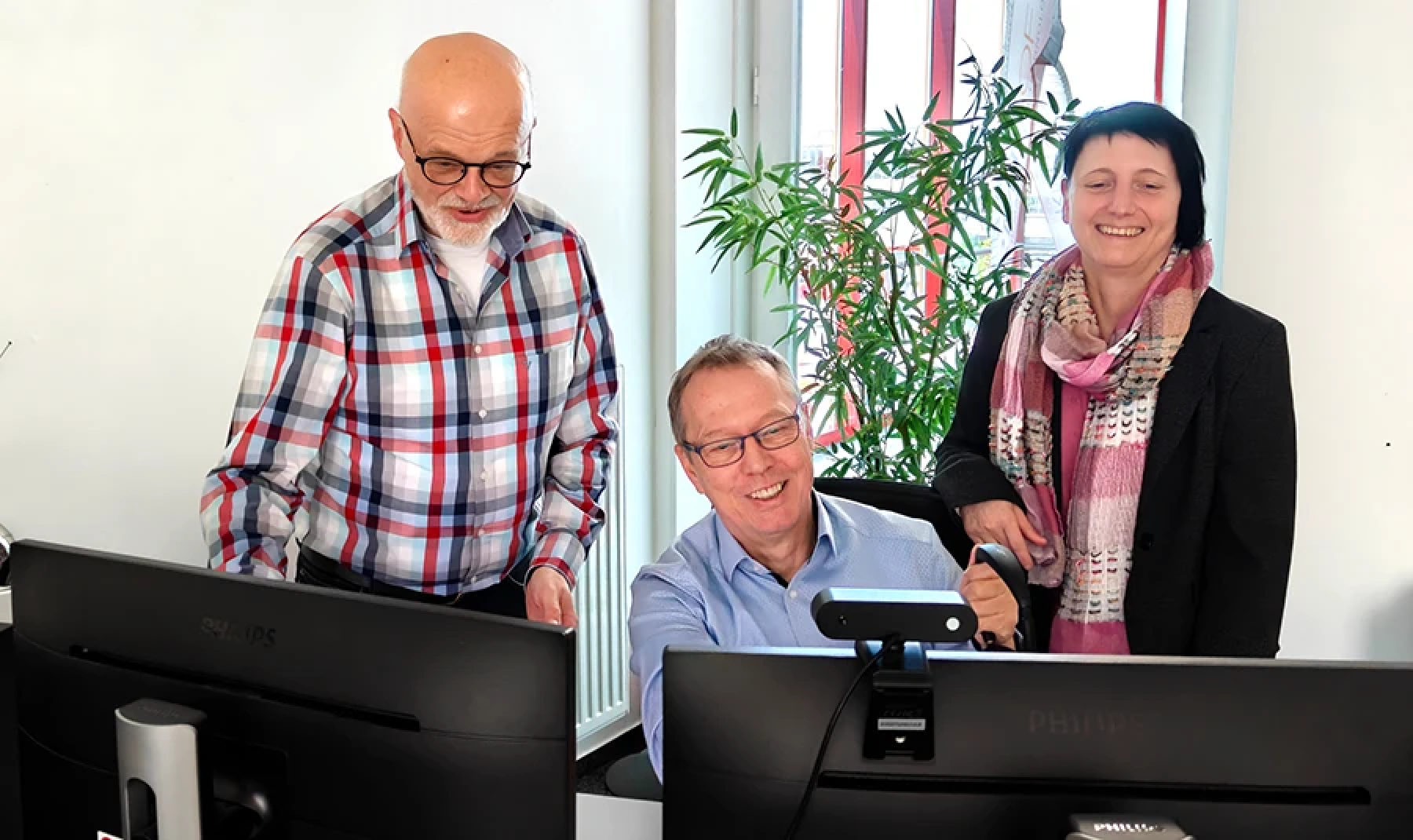 Das RMT Soft Service Team bespricht einen Servicevorgang am Bildschirm. Wir sehen zwei Herren sowie eine Dame. Der Herr in der Mitte sitzt vor zwei Bildschirmen, die anderen stehen.